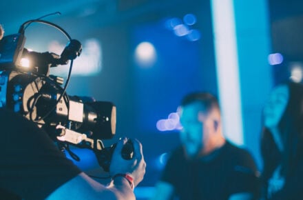 Videokuvaaja kuvaamassa pidellen kameraa kädessään.