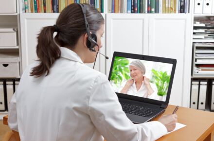 Sairaanhoitaja neuvoo asiakasta tietokoneen välityksellä.