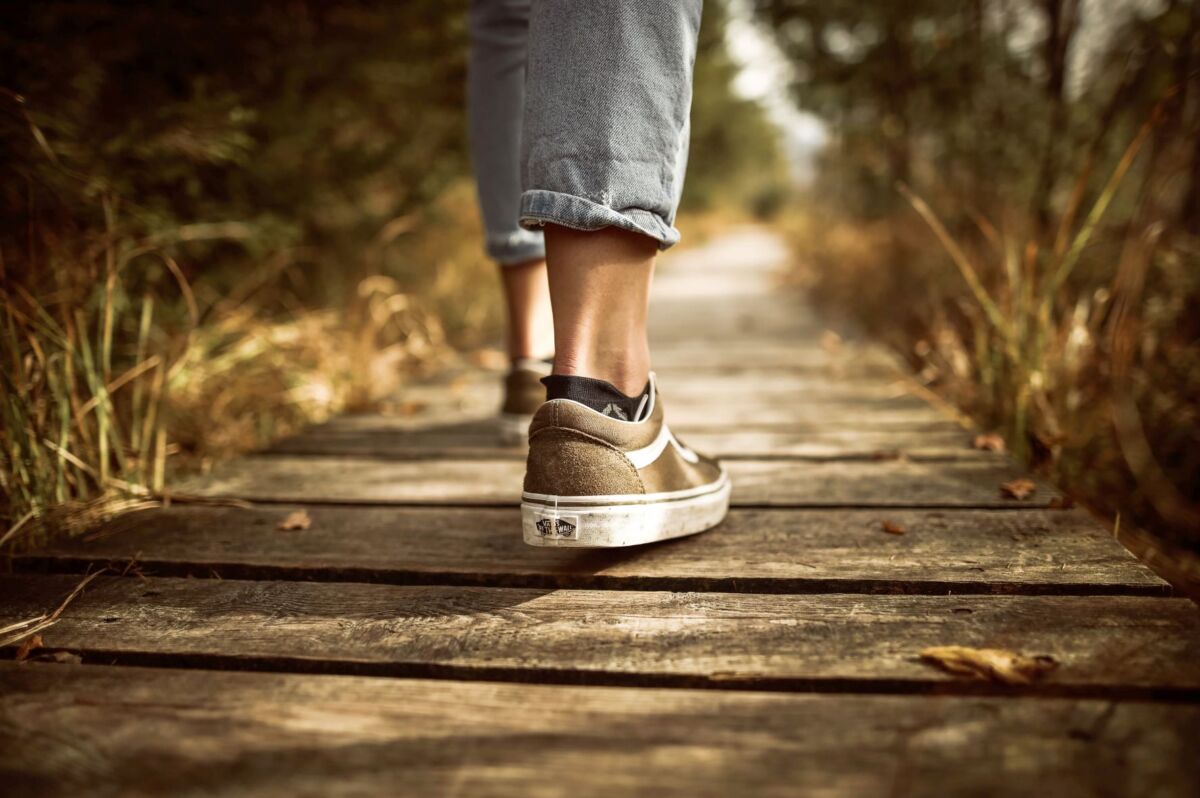 Ihminen kävelee pitkospuilla, kengät näkyvät