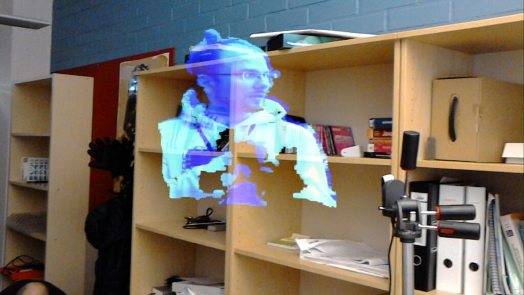 Laboratoriotilassa rakeinen sinertävä hologrammi ihmispäästä ja -rintakehästä.