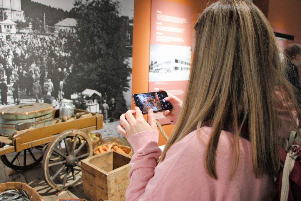 Henkilö ottamassa kännykällä kuvaa museonäyttelystä.