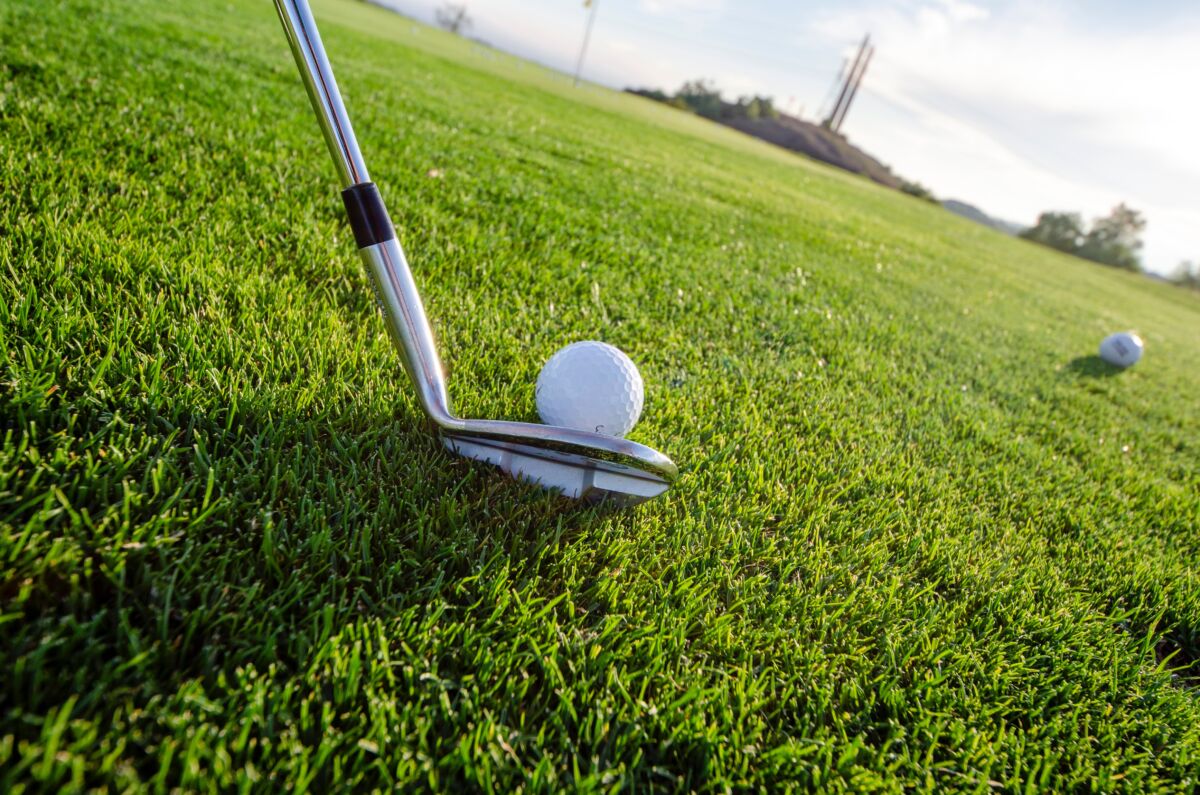 Golfmaila koskettaa golfpalloa golfkentällä.