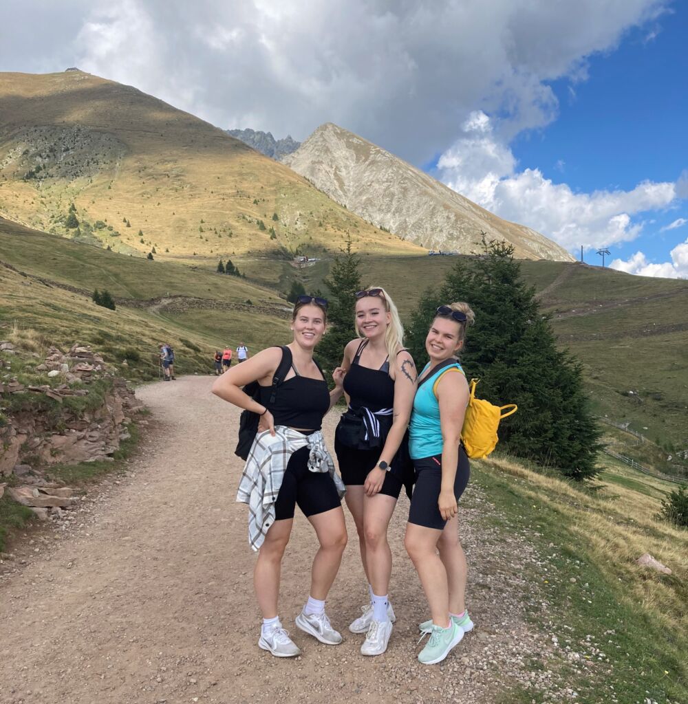 Kolme nuorta naista vuoristomaisemassa