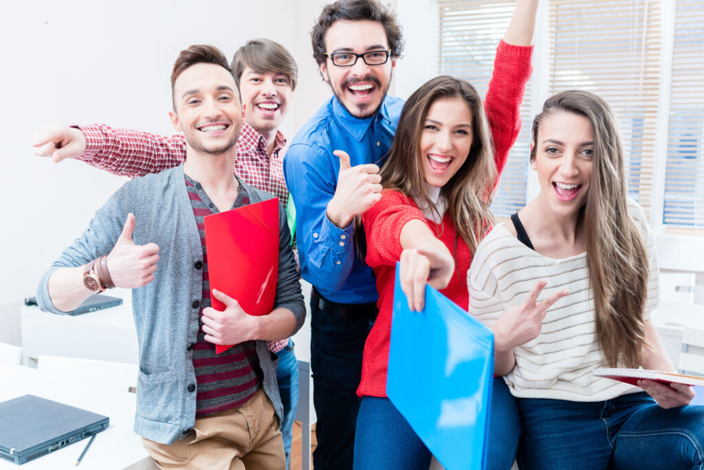 Group of students celebrating success in exams being cheerful throwing arms up