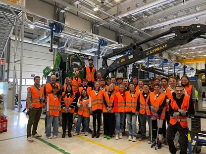 Group of people in a facotry facility. All of them are wearing safety vests.