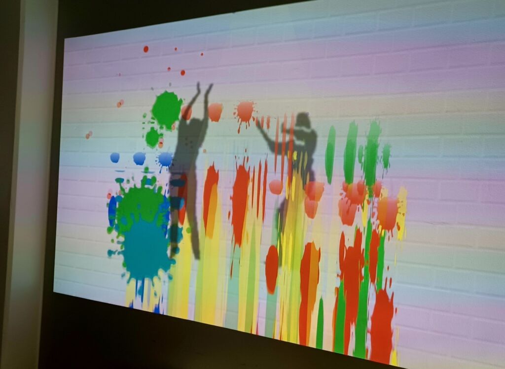 Seinälle heijastettu näyttö, jossa kirkkaan värisiä kuvia maalattuna