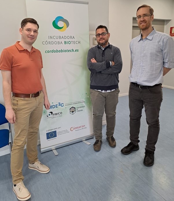 Three men standing in front of a roll-up with text Incubadora Corboda Biotech