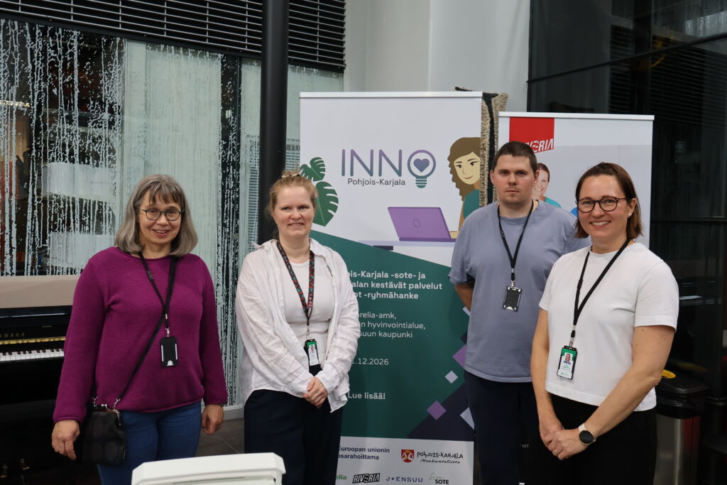 Neljä henkilöä seisoo roll up-telineen edessä, jossa lukee INNO Pohjois-Karjala
