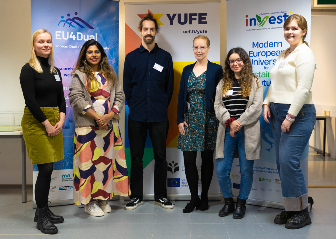 Group photo of six people standing in front of roll ups