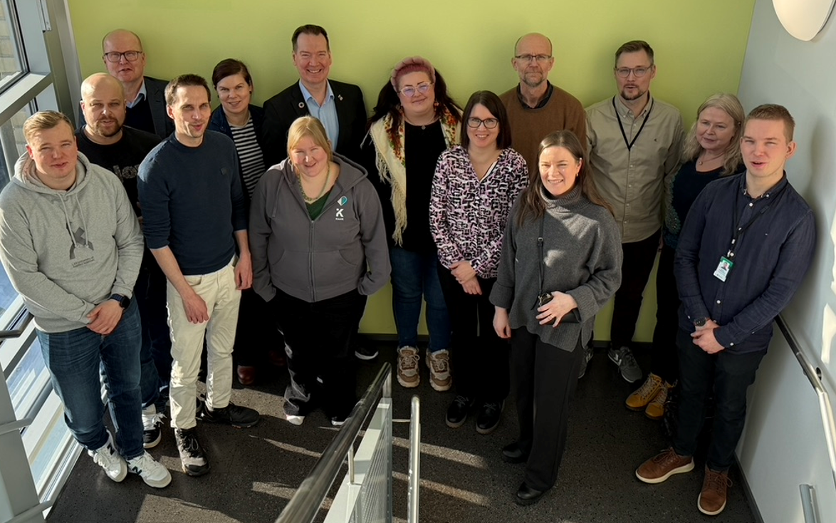 14 henkilöä seisoo ryhmäkuvassa portaikossa