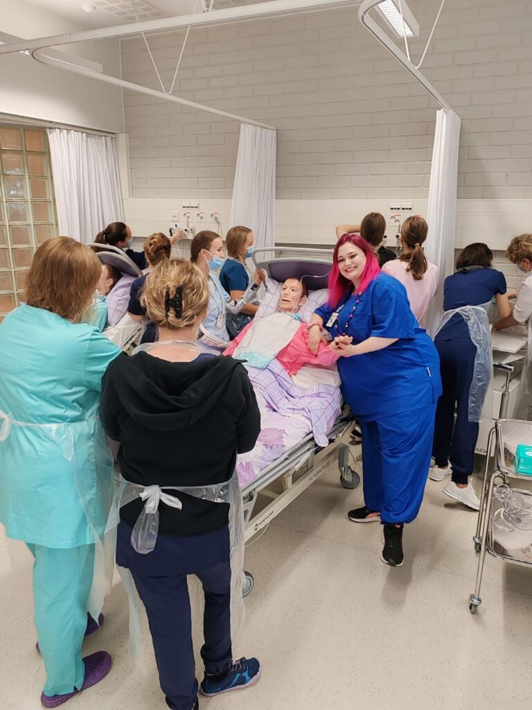 Sairaanhoitajakoulutuksen opetusluokka, jossa sairaalasängyssä opetusnukke. Sängyn ympärillä opiskelijoita.