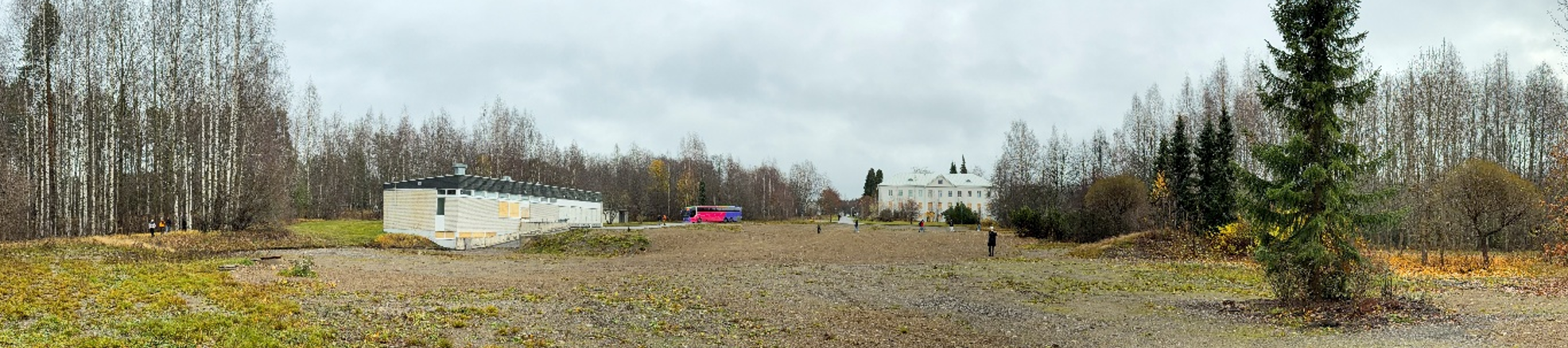Avara alue jossa taustalla vanha sairaalarakennus ja koivumetsää