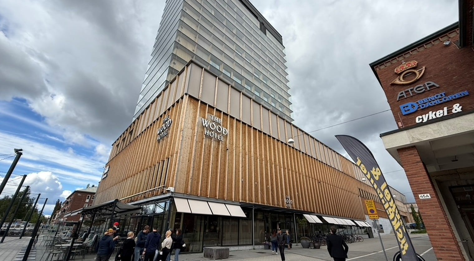 Näkymä kadulta korkeasta rakennuksesta, jonka ulkoverhoilussa käytetty puuta.  Rakennuksen seinässä teksti The Wood Hotel.